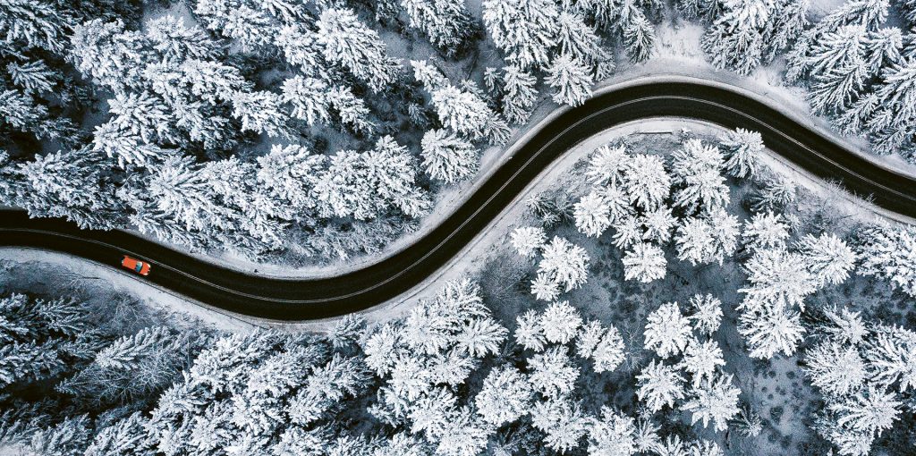 En bil på en slingrande väg genom snötäckt skog