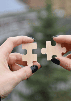 Närbild på ett par händer som håller pusselbitar mot varandra.