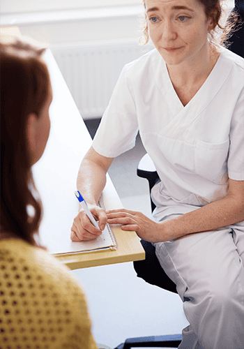 En läkare och en kvinna som samtalar vid ett skrivbord.