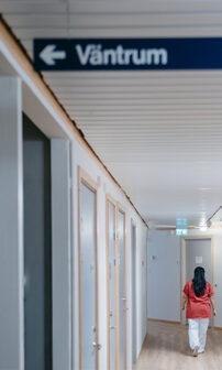 En skylt med texten väntrum hänger i en sjukhuskorridor.