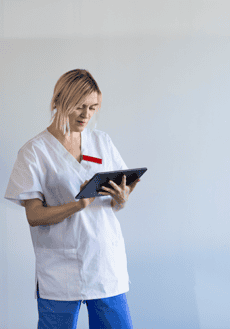 En läkare står och läser på en digital läsplatta.