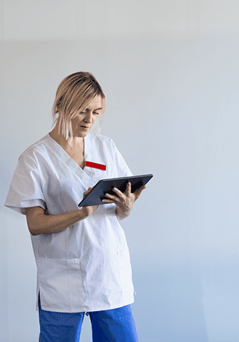 En läkare står och läser på en digital läsplatta.